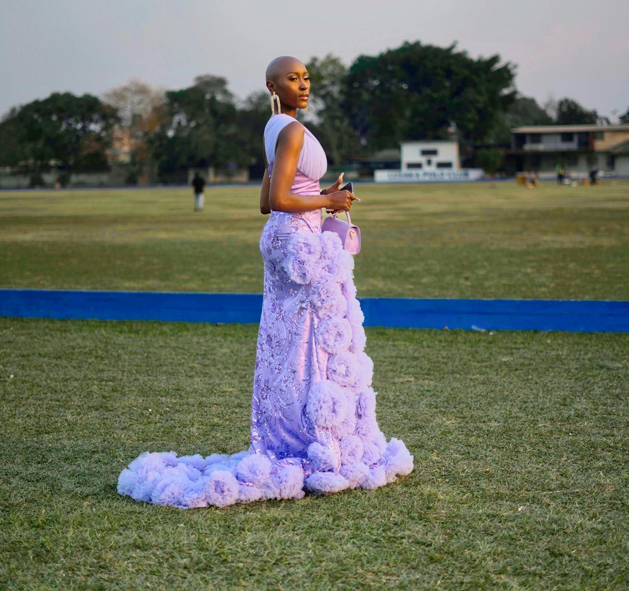 services-06 A stylish woman poses in a lavender gown on a grassy field, showcasing elegance and fashion.